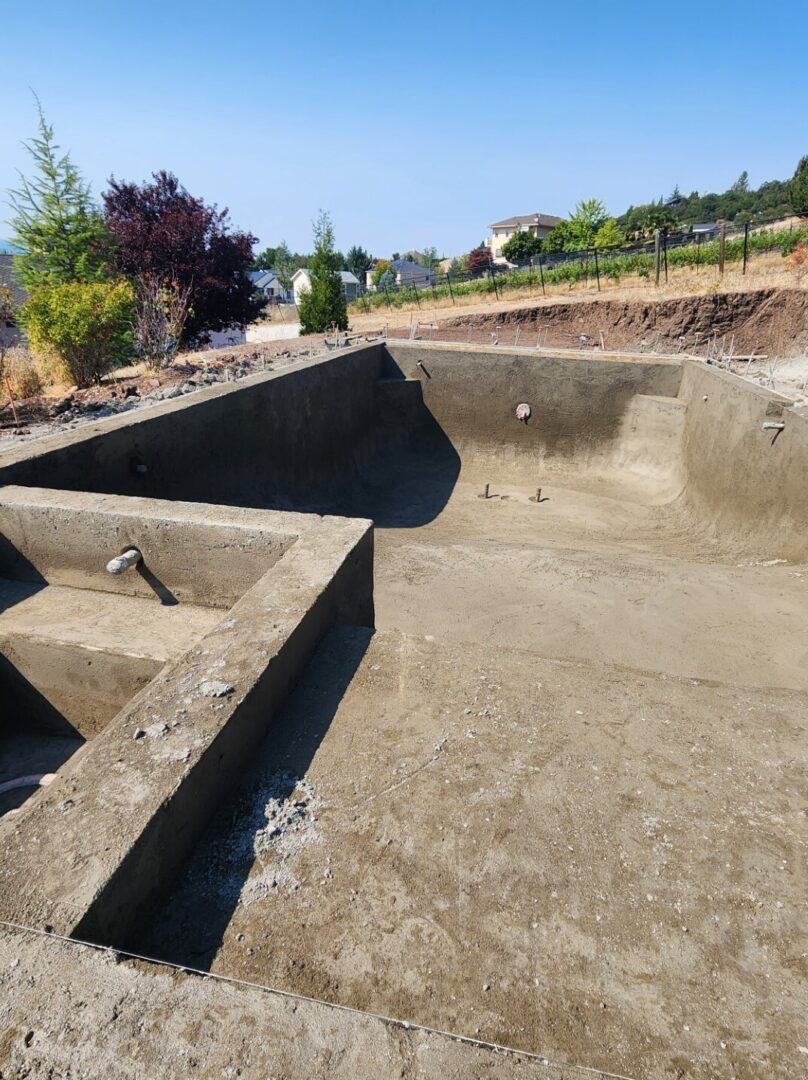 A concrete pool with steps and a ramp.